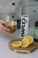 Holding a glass of Maple Amaretto Sour made with sparkling Maple 3 water.