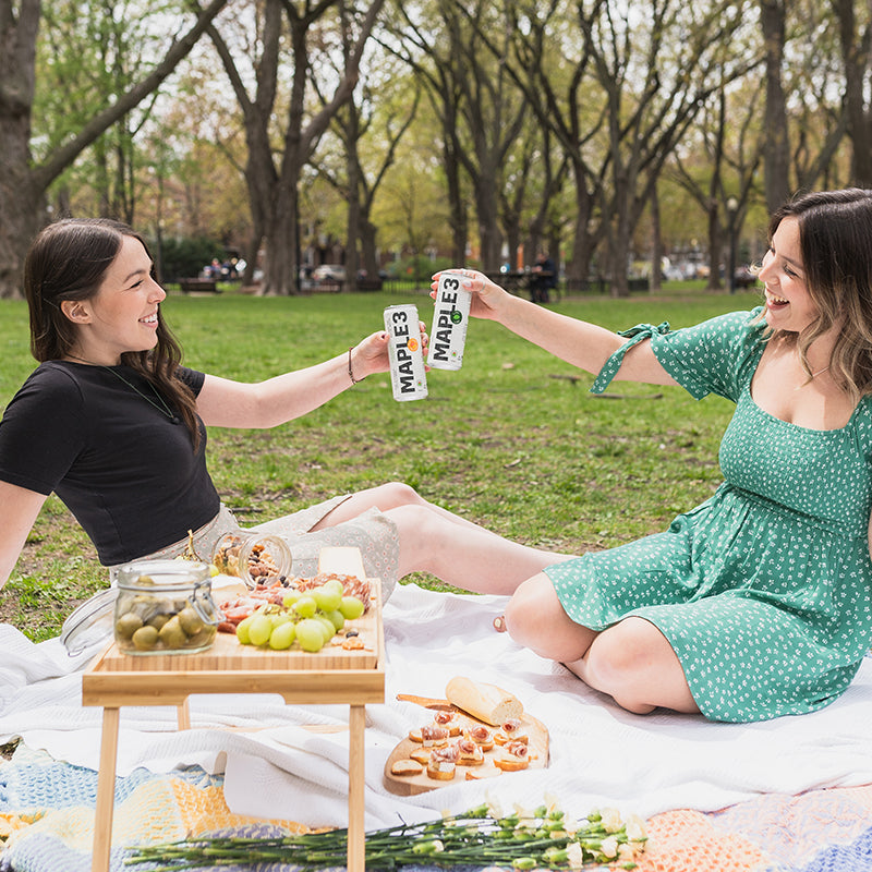 two girls drinking Maple 3 sparkling maple water at their picnic